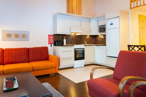 科林基拉Kolin Lotus Cottages的一间带两把橙色椅子的客厅和一间厨房