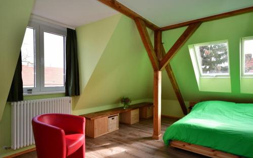 波茨坦Apartment Alter Fritz的绿色卧室,配有床和红色椅子
