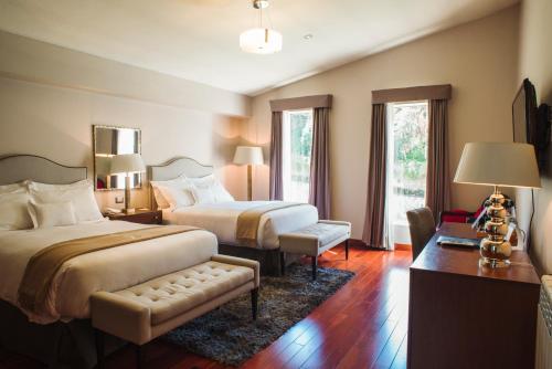 库斯科Atiq Boutique Hotel的酒店客房带两张床和一张桌子以及椅子。