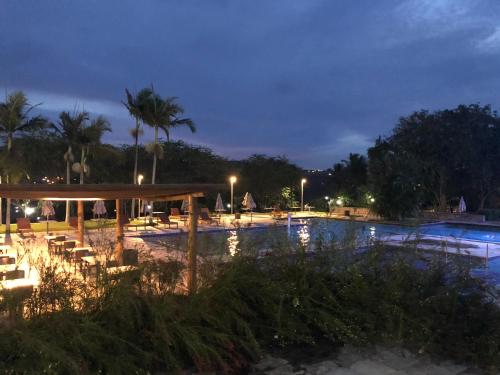 格拉瓦塔Flat 4 Suites Hotel Portal Gravata的夜间游泳池,配有椅子和灯