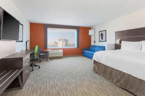 德斯普兰斯Holiday Inn Express & Suites Chicago O'Hare Airport, an IHG Hotel的酒店客房配有一张床、一张书桌和一台电视。