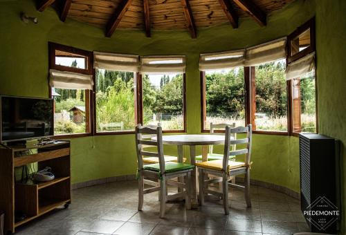 普埃洛湖Cabaña Piedemonte的一间带桌椅和窗户的用餐室