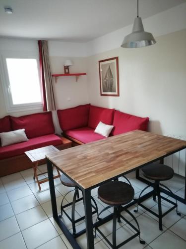 卡尔康LES GRANDS PINS的客厅配有红色的沙发和木桌