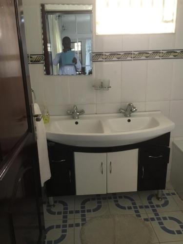 卡巴莱Kigezi Gardens Inn的一间带水槽的浴室和镜子里的人