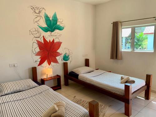 瓜埠Kawah Padi Garden Villa Langkawi的一间卧室设有两张床,墙上挂着一幅画