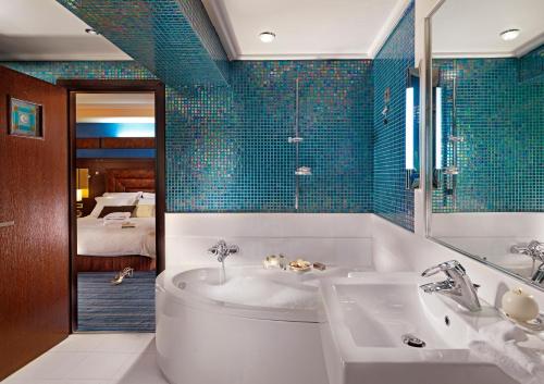 雅典雅典市中心皇冠假日酒店的一间带浴缸和水槽的浴室以及一间卧室