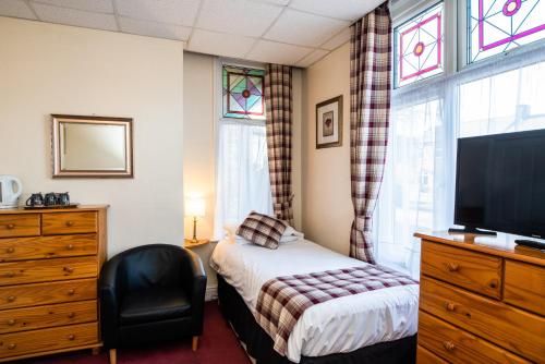 马奇铜锣湾旅馆的一间卧室设有一张床、一台电视和一个窗口。