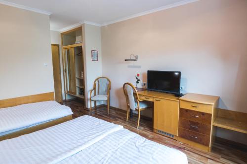 SemičHOTEL SMUK的酒店客房设有两张床和一张书桌及电视