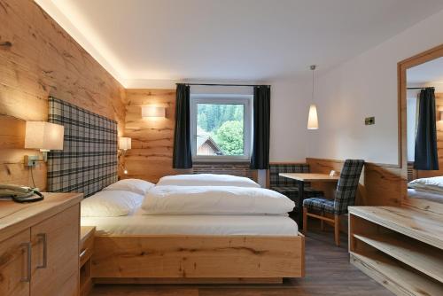 奥蒂塞伊Hotel Garni Vanadis的一间卧室设有两张床、一张桌子和一个窗口