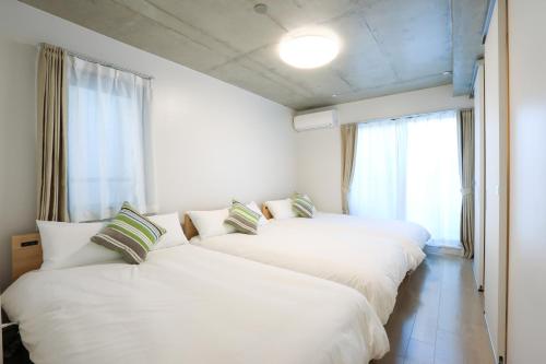 东京Laffitte Tokyo WEST的带窗户的客房内的3张白色床