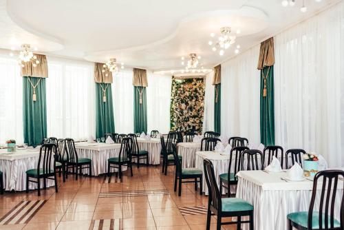 赫梅利尼茨基Lyube的一间设有白色桌椅和绿色窗帘的餐厅