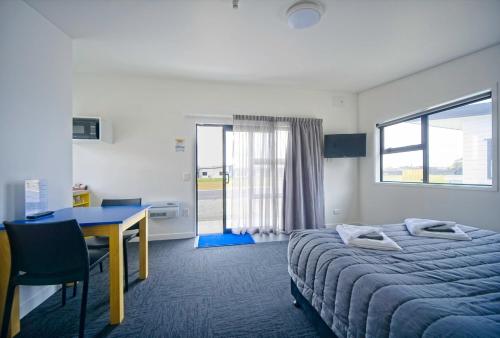 霍基蒂卡Hokitika's Kiwi Holiday Park and Motels的配有一张床、一张桌子和一张桌子的酒店客房