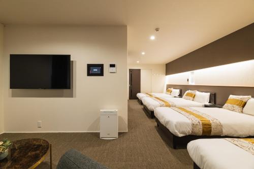 长崎GRAND BASE Nagasaki City的一间带平面电视的酒店客房内的一排床位