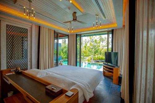 纳泰海滩Baba Beach Club Natai Luxury Pool Villa Hotel by Sri panwa - SHA Plus的一间卧室配有一张床、一台电视和一个游泳池