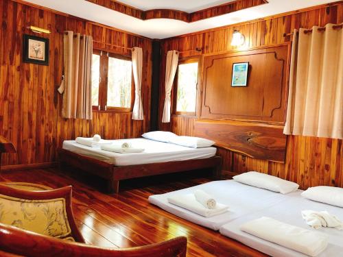 Ban Khao Kariang (1)คุ้งน้ำ รีสอร์ท นครนายก的木墙客房的两张床