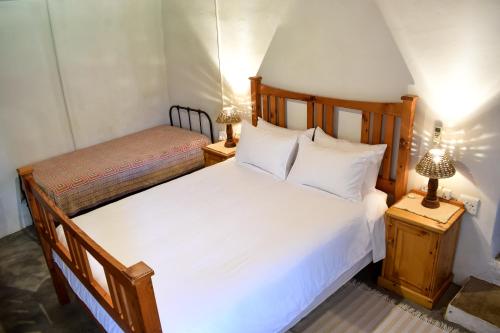 阿仕顿Die Ou Huis Accommodation的卧室配有一张白色大床和两盏灯。