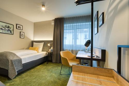 因戈尔施塔特NYCE Hotel Ingolstadt的配有一张床和一张书桌的酒店客房