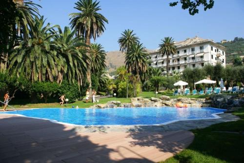 热那亚Savoia Apartments的棕榈树度假村内的游泳池以及大楼