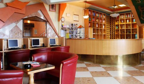 萨拉热窝BM酒店的餐厅设有酒吧,配有红色椅子和柜台