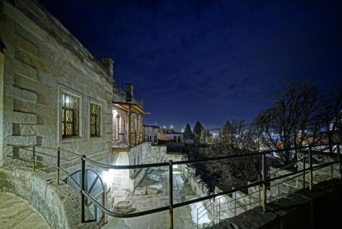 格雷梅Naraca Cave House的石头建筑,晚上有栏杆和楼梯