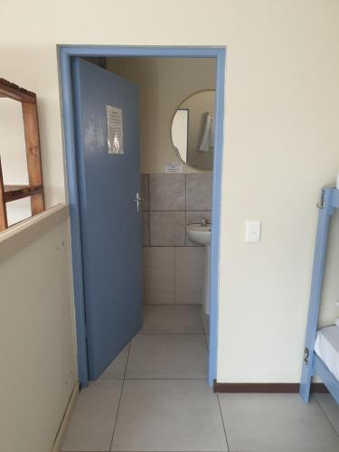 普利登堡湾Amakaya Backpackers Travellers Accommodation的浴室设有蓝色门和水槽