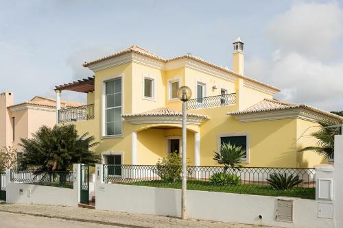 法鲁Laguna Formosa - Holidays in Algarve的白色围栏的黄色房子