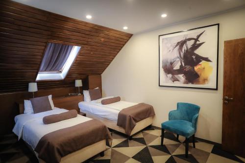 波亚纳布拉索夫Royal Boutique Hotel Poiana Brasov的酒店客房,设有两张床和一张蓝色椅子
