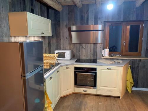 Saint-Apollinaire-de-RiasLa bergerie的厨房配有白色橱柜和冰箱。