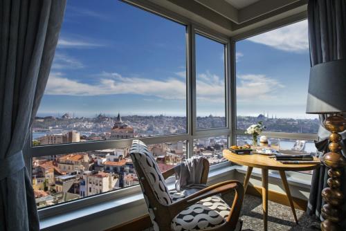 伊斯坦布尔马尔马拉佩拉酒店的窗户前配有桌椅的房间