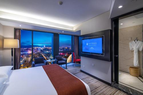 贵阳贵阳铂尔曼大酒店的一间酒店客房,配有一张大床和一台平面电视