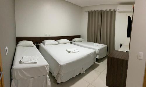 大瓦尔泽亚Hotel Tainá - Aeroporto Cuiabá的酒店客房设有两张床和电视。