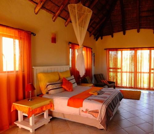 比勒陀利亚Baobab - NUDE - SunEden Family Naturist Resort的一间卧室配有带橙色窗帘的大床