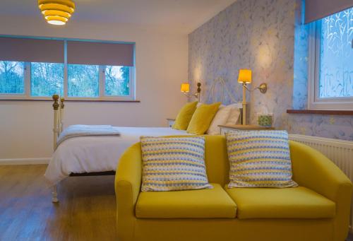 黑尔斯沃思Blyth Lodge B&B的一间卧室配有一张床和一张黄色的沙发