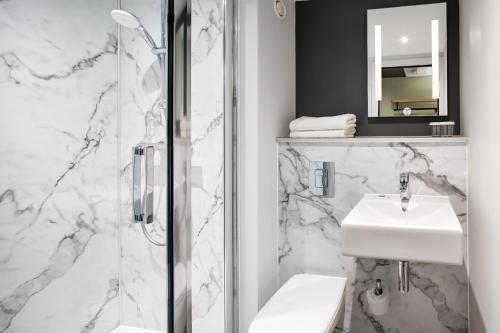 史云顿ibis budget Swindon的白色的浴室设有水槽和淋浴。