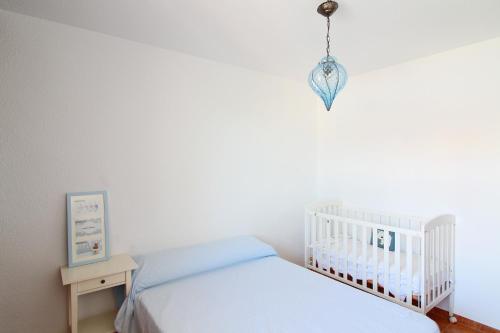 萨贡托Global Properties, Adosado en la playa con piscina的一间白色卧室,配有一张婴儿床和吊灯