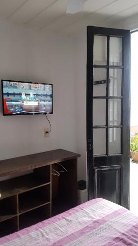 布宜诺斯艾利斯卡洛斯葛戴尔旅馆的一间卧室配有一张桌子和一台墙上的电视。