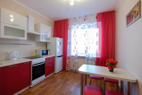 托木斯克ОК! Советская, 60 №1的厨房配有红色橱柜和桌椅