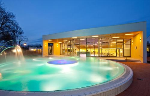巴特拉德克斯堡德尔帕克斯姆维塔酒店的一座带喷泉的建筑前方的大型游泳池