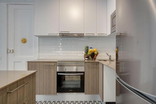 巴塞罗那LucasLand Apartments Barcelona的厨房配有白色橱柜和炉灶烤箱。