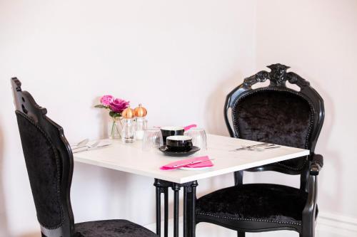 托基The Rosewood Torquay的一张桌子、两把黑色椅子和一张白色的花桌