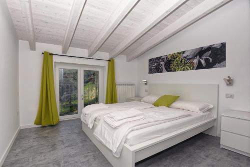 特雷莫西内Casa negli Ulivi的白色的卧室设有一张大床和一个窗户