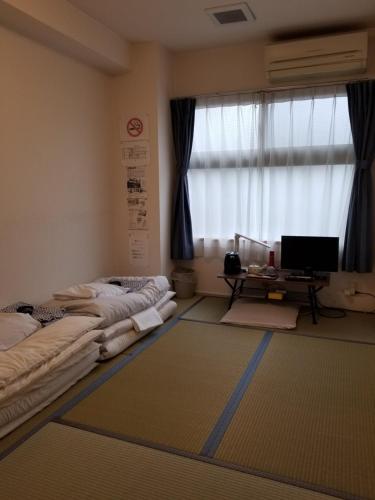 京都Ika Tsumesyo的客房设有两张床、一张桌子和一个窗户。