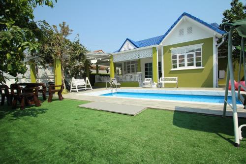 华欣Little home poolvilla的一个带游泳池和房子的后院