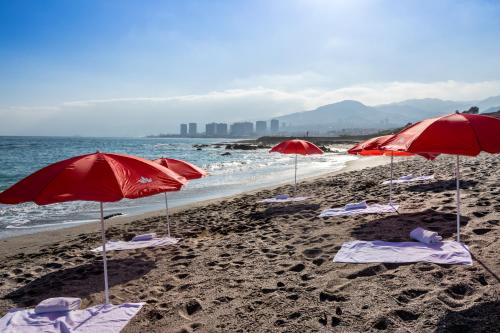 安托法加斯塔吉奥特尔安托法加斯塔公寓的沙滩上沙滩上摆放着红色遮阳伞和椅子