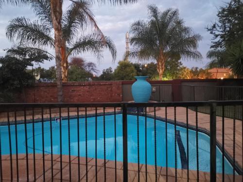 比勒陀利亚Klyne Jiweel Guesthouse的蓝色的花瓶坐在游泳池旁的围栏上