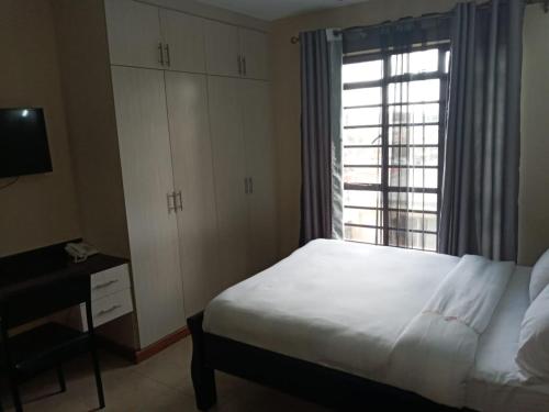 内罗毕Nairobi west suite的卧室配有白色的床和窗户。