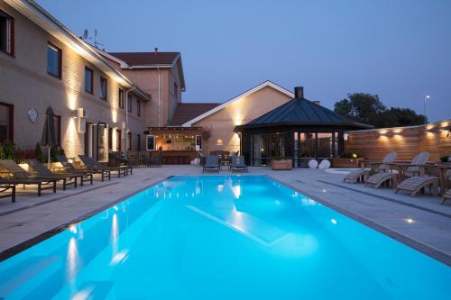 耶尔费拉巴尔卡欢迎酒店的一座带椅子的游泳池以及一座建筑