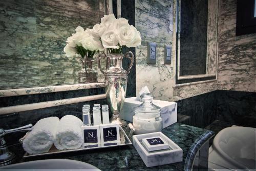 亚松森Nino Hotel Boutique的浴室柜台配有花卉和毛巾的花瓶