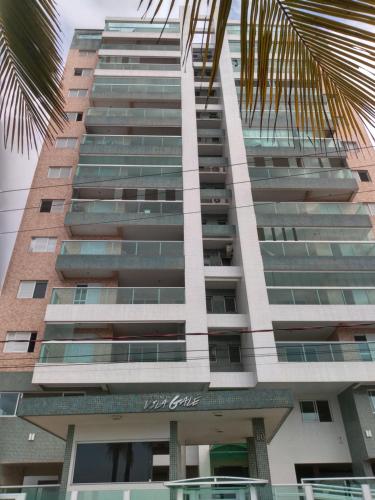 蒙加瓜Apartamento Temporada pé na areia的一座高大的建筑,前面有一棵棕榈树