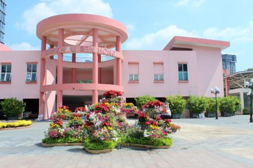 胡志明市Liberty Hotel Saigon Greenview的前面有鲜花的粉红色建筑